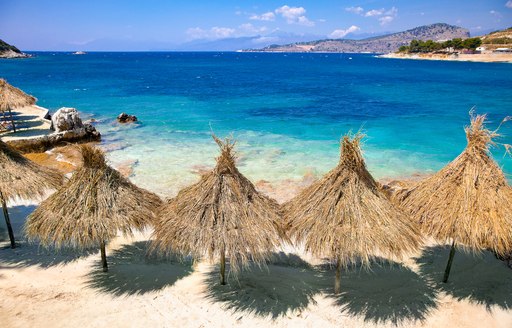 Straw beach umbrellas on a sandy beach facing a blue sea