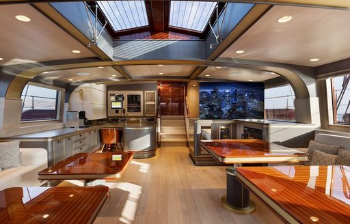 Overview of the interiors onboard sailing yacht charter SALLYNA, several tables and fittings surrounded by large windows