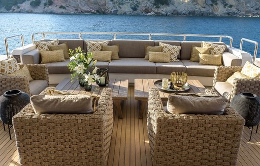 Alfresco seating area onboard charter yacht MR T, with plush grey seating and views of a bay