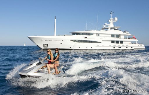 Charter yacht SPIRIT side profile with guests enjoying a jet ski