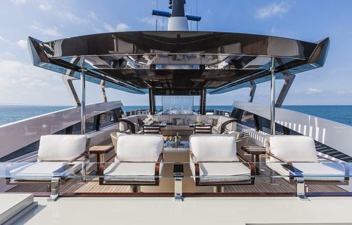 Overview of the sundeck onboard charter yacht PARILLION, four sun loungers in the foreground with panoramic views of the sea.