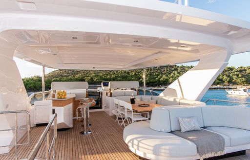 Flybridge onboard charter yacht VESTA, lounge area in the foreground and dining aft with a wet bar to port side