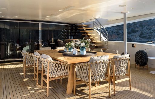 Alfresco dining area onboard charter yacht MR T, long table surrounded by white seats