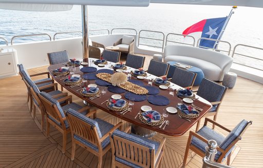 Alfresco dining option onboard charter yacht PURPOSE, long table with dark blue upholstered chairs