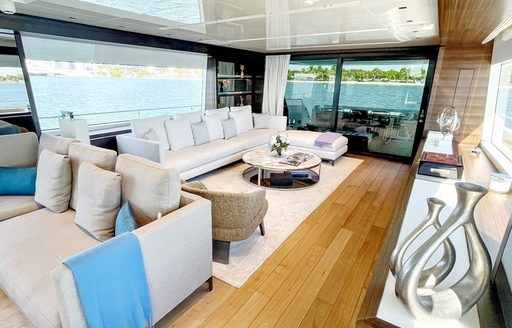 Overview of the main salon onboard charter yacht C-DAZE, spacious lounge in the background with a sofa forward, surrounded by large windows