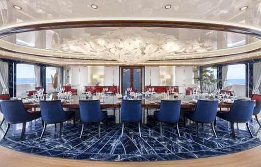 Formal dining area onboard charter yacht AHPO, long dining table surrounded by blue seats