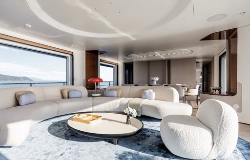Main salon lounge onboard charter yacht LUZ DE MAR, large white sofas facing in, surrounded by wide-reaching windows