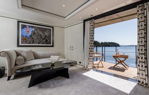 A view which shows the sofa inside of a yacht, and the balcony which extends outside of it