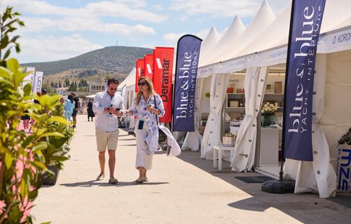 Line of exhibitor tents at MEDYS with two visitors walking by