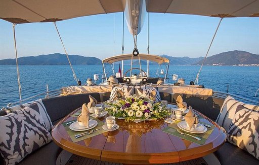 Alfresco dining table on board luxury yacht Savarona with mountains in background 
