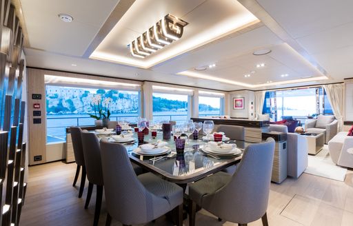 formal dining area flanked by large windows on board luxury yacht ONEWORLD 