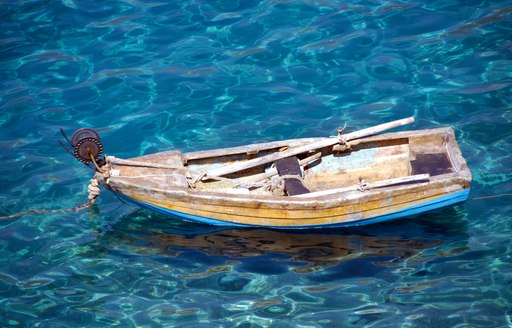 Tiny boat floating in crystal waters on Skopelos island in the Sporades, Greece