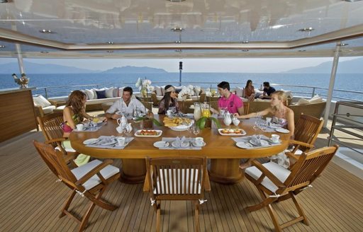 Charter guests dining on the exterior of motor yacht O'MEGA