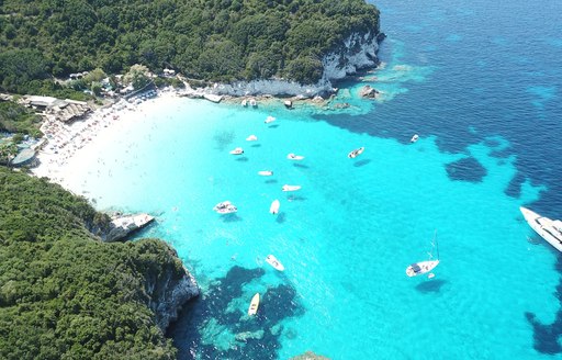 Aerial shot of bay in Caribbean with boats on the blue water and sandy beach