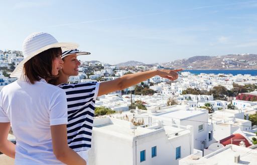 two female tourist look out over the white-building town on Mykonos