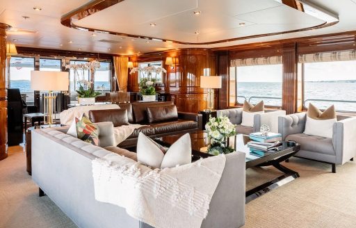 Overview of the lounge in the main salon onboard superyacht charter REMEMBER WHEN with plush neutral-toned seating surrounded by large windows