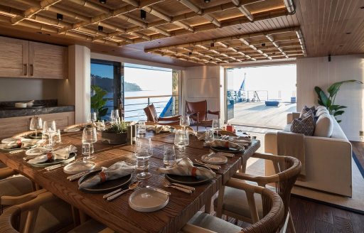 Interior dining area onboard charter yacht KING BENJI, large table with large openings to exterior decks on two sides
