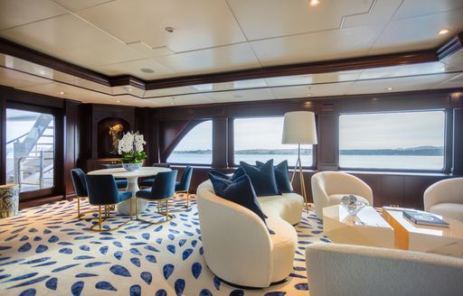 Upper salon onboard charter yacht PURPOSE, with plush white seating and large windows