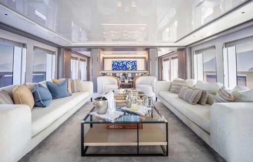 Overview of the main salon onboard charter yacht FORTUNA, spacious lounge area with plush seating and a central coffee table 