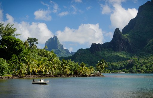Boat in Cooks Bay with Moua Puta mountain in the background in a green jungle landscape on the tropical island of Moorea, near Tahiti in the Pacific archipelago French Polynesia.