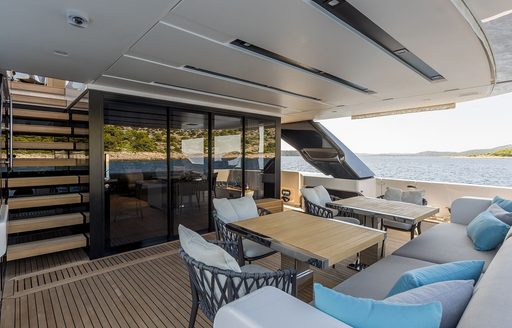 Aft main deck onboard charter yacht JICJ, with central alfresco dining area and stairs leading to upper deck