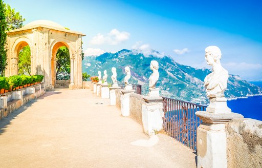 Beautiful stone busts set along colonnade walkway with stone arch in Italy