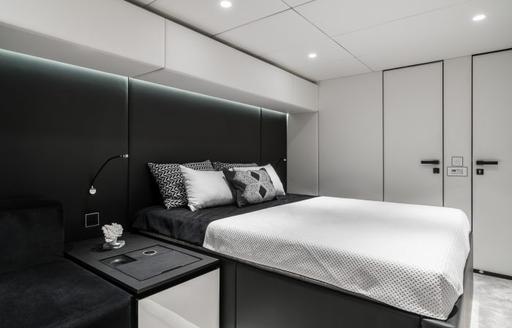 Guest cabin onboard charter yacht ABOVE & BEYOND, forward facing central berth with monochrome styling
