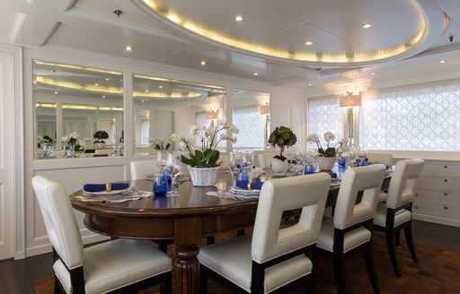 formal dining round large wooden table in dining salon on board motor yacht BINA 