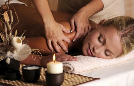 A blonde haired woman enjoys a back massage from a masseuse