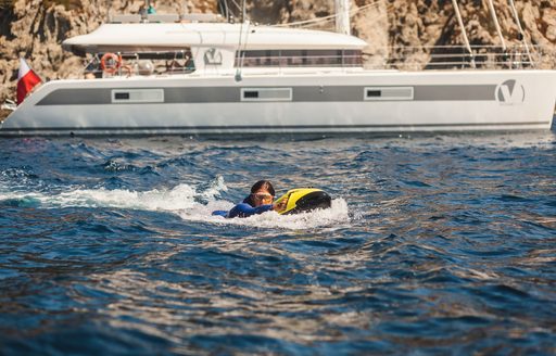 charter guest tries out the SEABOB with luxury catamaran in the background on a Tahiti vacation
