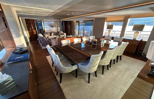 Interior dining area onboard charter yacht LE VERSEAU, with a long table and upholstered chairs, surrounded by large windows