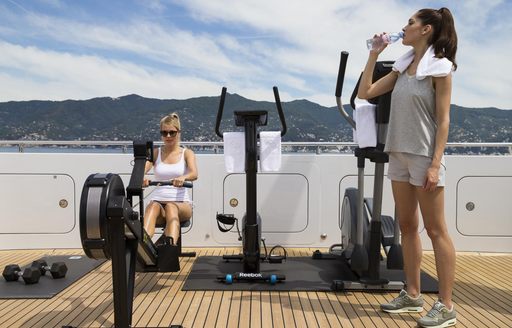 A couple of ladies using the on-deck gym onboard a yacht