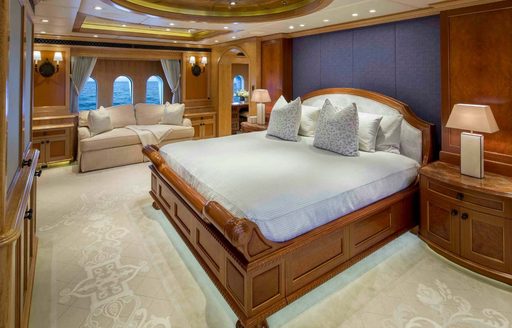 Master cabin onboard charter yacht UNBRIDLED, central berth facing port with seating and windows in background 
