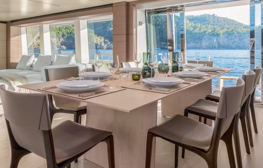 Fully laid dining table on SANGHA superyacht with doors open and sea in background
