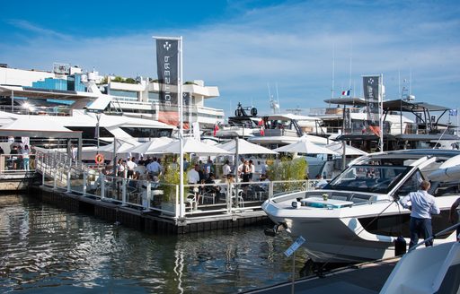 Exhibitor stand at the Cannes Yachting Festival with motor yachts berthed in the foreground