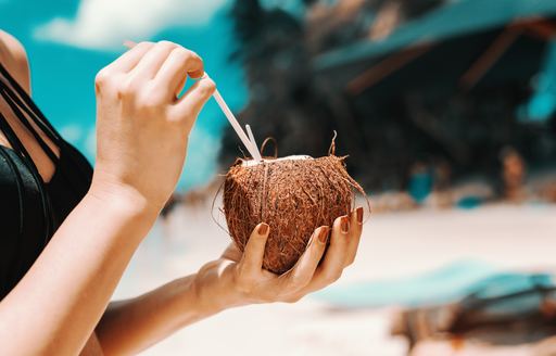 Woman holds coconut cocktail in the Caribbean