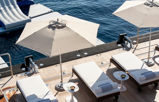 Close up view of the poolside sunloungers and parasols onboard charter yacht ARBEMA