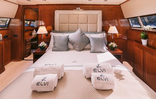 Master cabin onboard charter yacht ELVI, central berth facing forward with branded towels and window to port and starboard