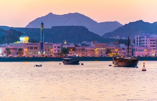 oman port by night, little wooden boats with mountain backdrop