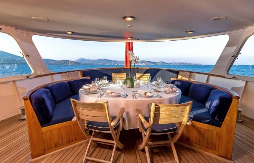 Alfresco dining area onboard charter yacht SECRET LIFE, circular seating arrangement with blue upholstery