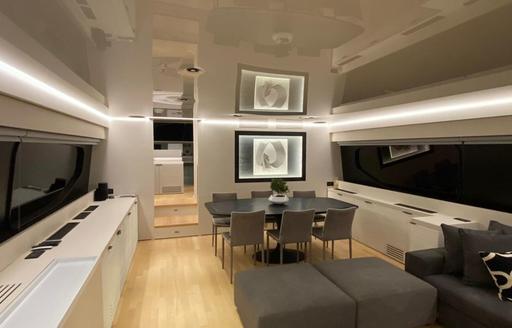 Main salon onboard charter yacht ALFA, lounge area in the foreground and dining area aft