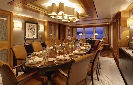 Overview of the dining room onboard charter yacht LADY BRITT, central dning table with ornate decoration and a window in the background