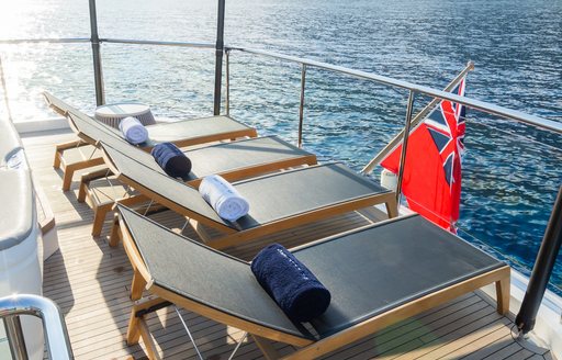 A row of sunloungers looking out over the sea on the aft deck of charter yacht MInor Family Affair