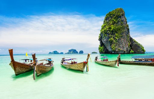 traditional fishing boats line up on shoreline of beautiful Thailand beach