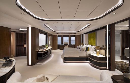 Overview of the master cabin onboard charter yacht MALIA, central berth facing port with plush seating in the foreground and windows in the background