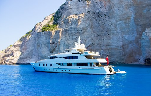 A white motor yacht is anchored in blue waters of the Mediterranean