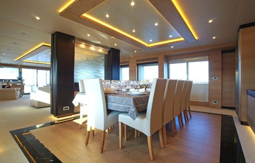 Interior dining area in the main salon onboard charter yacht TATIANA I, long table with white upholstered chairs