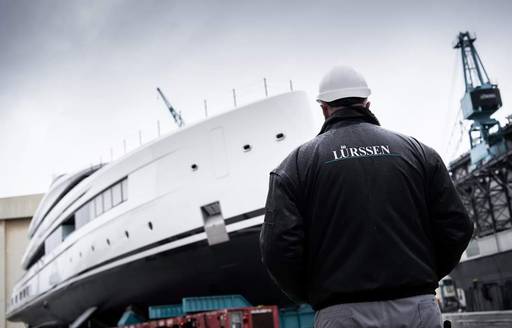 A team member of Lurssen standing on the ground watching the launch of superyacht CALI
