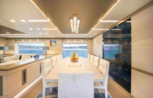 Overview of the interior dining area onboard boat charter CHARADE, long white table and matching chairs