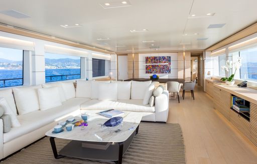 Superyacht NARVALO main salon, with lounging area with white sofas and formal dining set-up